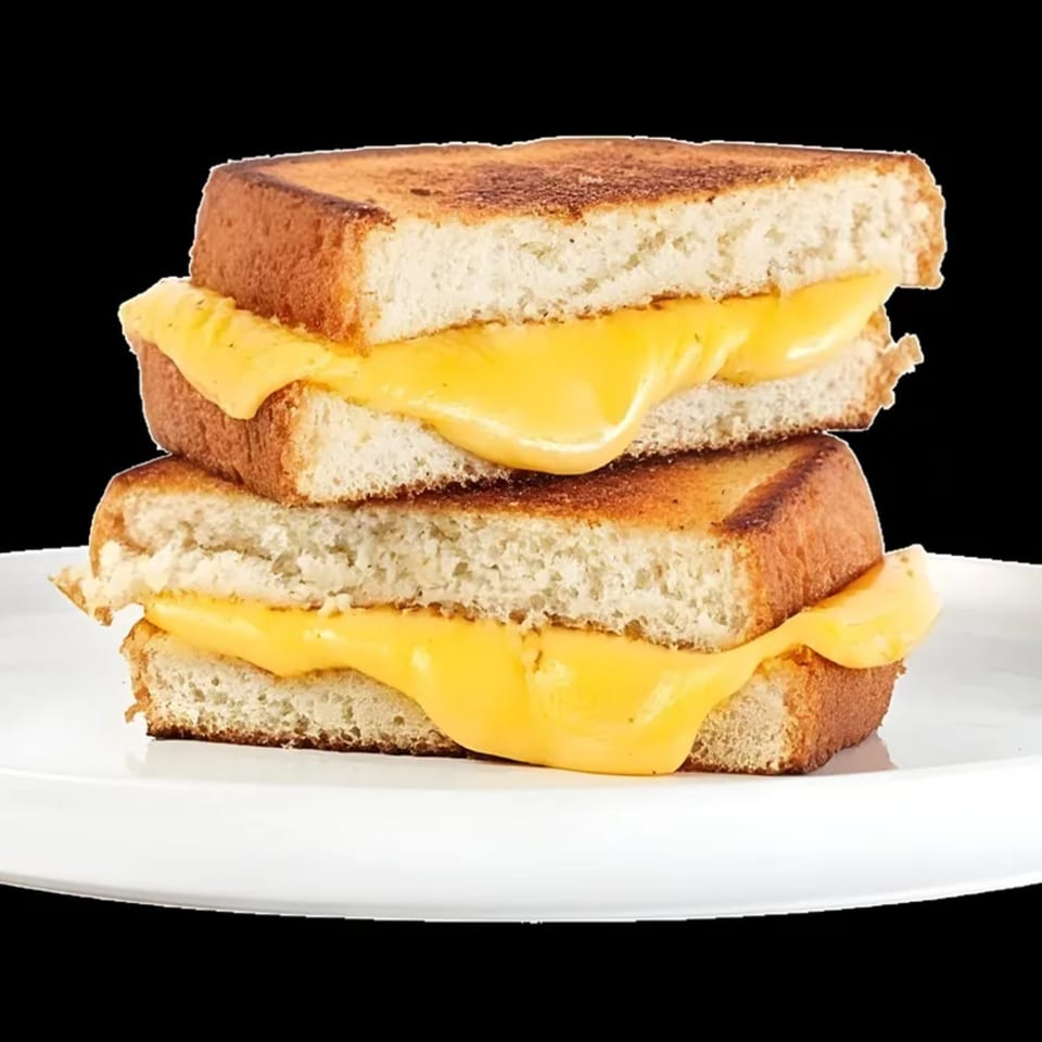Two halves of a grilled cheese sandwich, stacked on a white plate, with melted yellow cheese oozing out.