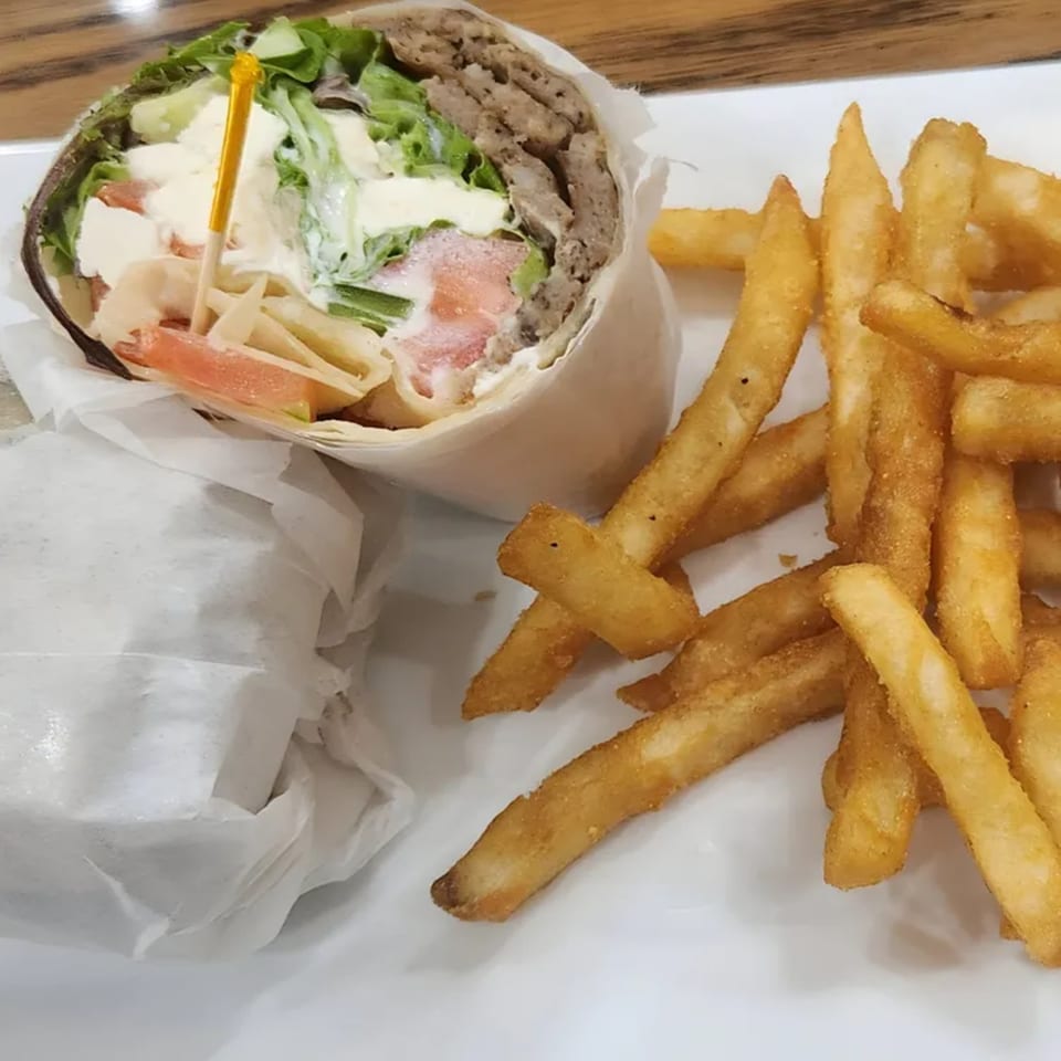 A Shore Road Diner gyro wrap with meat, lettuce, tomatoes, and sauce, served with golden french fries.