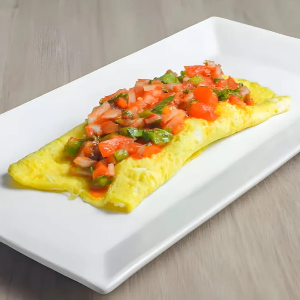 Shore Road Diner's omelet topped with fresh diced tomatoes, onions, and green herbs on a white plate.
