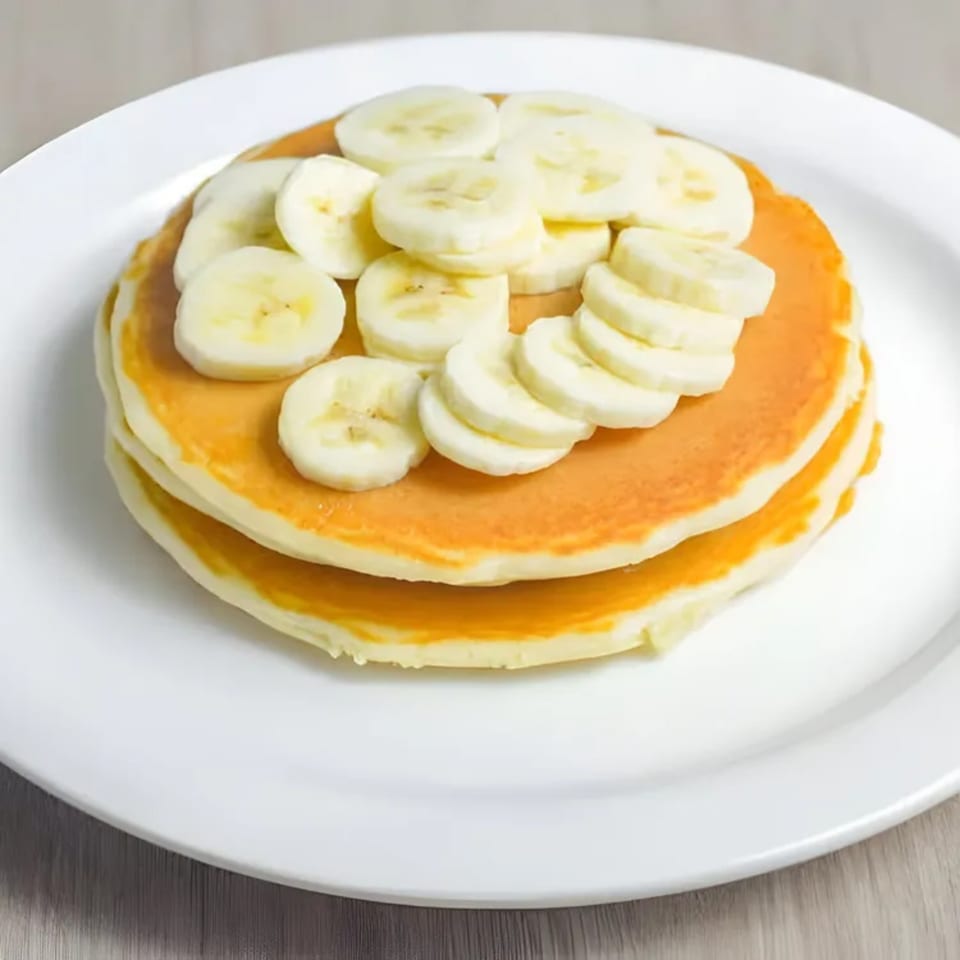Fluffy pancakes topped with sliced bananas on a white plate at Shore Road Diner.